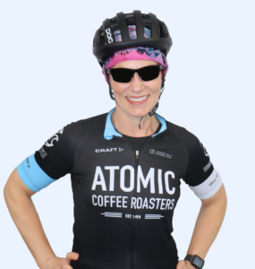 Theresa Conway wearing a black tee shirt, sunglasses, a pink bandanna and a bike helmet.